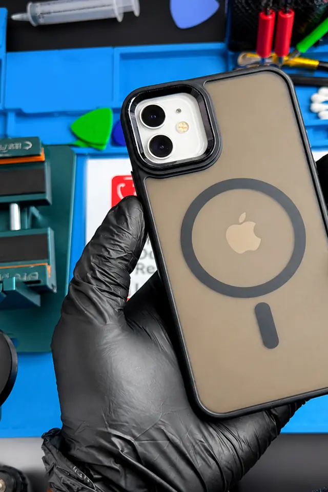 A repaired iPhone 12 in a technician&rsquo;s gloved hand over the MobiDokta repair mat