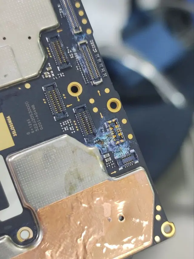 Liquid corrosion on an iPhone logic board under macro magnification